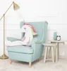 A plush unicorn toy is sitting on a teal armchair next to two small side tables. Podgląd zdjęcia produktu