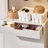 A close-up view of a drawer in a white cabinet, revealing various storage items like baskets, containers, and personal care products. Anteprima dell’immagine prodotto