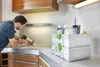 A man is using a caulking gun to apply sealant to a countertop in a kitchen setting. A tool organizer box with various items is on the countertop. Anteprima dell’immagine prodotto