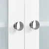 A close-up view of two silver cabinet knobs on white cabinet doors. Podgląd zdjęcia produktu