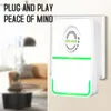 A white electricity saving box plugged into a wall socket, with a blurred living room in the background. Podgląd zdjęcia produktu