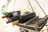 A wooden wine rack hanging from chains, holding three bottles of red wine. Produktbild-Vorschau