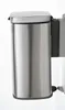 A close-up of a silver trash can with a black pedal and a gray mounting bracket. Náhľad obrázku produktu