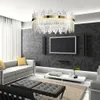 A modern living room with a gray sofa, black ottomans, a large television, and a decorative chandelier. Produktbild-Vorschau