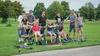 A family is gathered in a park with several scooters, some of which are being ridden by children. Náhľad obrázku produktu