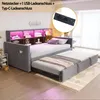A grey upholstered daybed with a pull-out trundle bed, featuring built-in shelving with LED lighting and a power outlet module. Voir les images du produit
