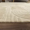 A close-up view of a cream-colored rug with a geometric pattern, lying on a wooden floor. Anteprima dell’immagine prodotto