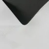 A close-up view of the underside and edge of a white, textured rug, showing the black, patterned backing. Produktbild-Vorschau