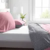 A close-up view of a bed with pink and gray striped bedding. Produktbild-Vorschau