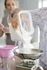 Two people in a kitchen, one is pouring sugar from a container into a scale. Anteprima dell’immagine prodotto