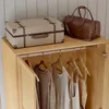 A wardrobe with clothing hanging inside and luggage on top. Náhled obrázku produktu