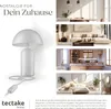 A collage showing a white retro-style table lamp and lifestyle images of the lamp in different rooms of a house (dining room, living room, kitchen, bedroom). Produktbild-Vorschau