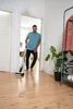 A man is cleaning a wooden floor with a cordless floor cleaner in a hallway. Anteprima dell’immagine prodotto