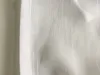 A close-up view of white fabric with vertical pleats. Produktbild-Vorschau