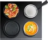 A top-down view of cookware and food items arranged on a black surface. Produktbild-Vorschau