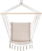 A hanging chair with a cushion and tassels, suspended from a wooden bar. Produktbild-Vorschau