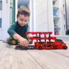 A young boy is playing with a toy car carrier truck on a wooden floor. Náhled obrázku produktu