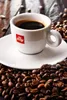 A cup of Illy coffee surrounded by coffee beans. Produktbild-Vorschau