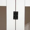 A close-up view of a black metal hinge connecting two white panels, likely part of a furniture item. Podgląd zdjęcia produktu