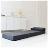 A gray foldable mattress is laid out on a white floor in front of a white cabinet. Podgląd zdjęcia produktu