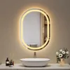 A modern bathroom vanity with a sink, faucet, and an illuminated oval mirror above it. Decorative items like a diffuser and flowers are also present. Podgląd zdjęcia produktu