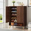 A wooden shoe cabinet with doors and adjustable shelves, filled with shoes, placed in a room with a window and a rug. Náhľad obrázku produktu