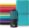 A stack of folded microfiber towels in various colors, with a rolled-up towel in a mesh bag in the foreground. Produktbild-Vorschau