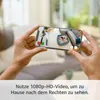 Hands holding a smartphone displaying a live feed from a security camera showing a dog in a bed. Anteprima dell’immagine prodotto