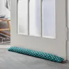 A teal and white polka dot door draft stopper lies on a gray floor in front of a white door. Produktbild-Vorschau