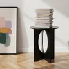 A black side table with a stack of books on top, placed next to a framed abstract artwork on a wooden floor. Anteprima dell’immagine prodotto