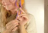 A person is styling colorful hair extensions. Produktbild-Vorschau