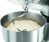 A close-up shot of a stand mixer with a dough hook mixing dough in a stainless steel bowl. Produktbild-Vorschau
