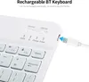 Close-up of a white rechargeable Bluetooth keyboard with a USB charging cable plugged in. Náhled obrázku produktu