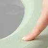 A close-up of a finger pressing on a textured green WC seat cushion. Podgląd zdjęcia produktu