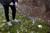 A person is using a trash grabber to pick up litter in an outdoor area with grass and trees. Anteprima dell’immagine prodotto