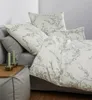 A bed with bedding and pillows, with candles on a side table. Produktbild-Vorschau