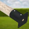 A close-up shot of a black metal post anchor attached to a wooden post, set against a blurred background of green grass and a blue sky. Produktbild-Vorschau