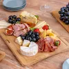 A charcuterie board filled with various cheeses, meats, fruits, and grapes, arranged on a wooden cutting board. Produktbild-Vorschau