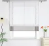 A window with a white and gray roman shade, a lamp on the left, and a vase of tulips on the right. Produktbild-Vorschau