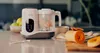 A baby food maker sits on a kitchen counter next to some fruits and vegetables. Produktbild-Vorschau
