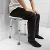 A person is sitting on a shower stool in a tiled bathroom. Produktbild-Vorschau