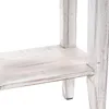 A close-up view of the distressed white wooden shelf and legs of a piece of furniture. Náhled obrázku produktu