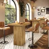 A bar or cafe setting with high tables and stools, featuring large arched windows with greenery outside. Produktbild-Vorschau