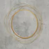 A gold circular mirror with thin gold wire-like accents on a textured gray background. Náhľad obrázku produktu