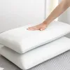 A hand pressing down on a white pillow, with another white pillow stacked underneath. Produktbild-Vorschau