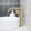 A close-up view of a gold faucet over a white sink with water flowing. Anteprima dell’immagine prodotto