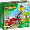 The image shows the packaging of a LEGO DUPLO fire truck set, with the toy fire truck and accessories depicted on a green and white background with cartoonish trees and a fence. Produktbild-Vorschau