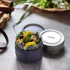 A close-up of a glass lunch container filled with salad, placed on a textured surface next to its lid and another container. Podgląd zdjęcia produktu