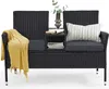 A black rattan bench with gray cushions, a yellow throw blanket, a pillow, books, and a vase with greenery. Produktbild-Vorschau