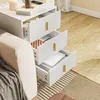 SoBuy Nachttisch FBT115-L-E-W in Weiß neben einem Sofa platziert, geöffnete Schubladen zeigen Alltagsgegenstände Produktbild-Vorschau